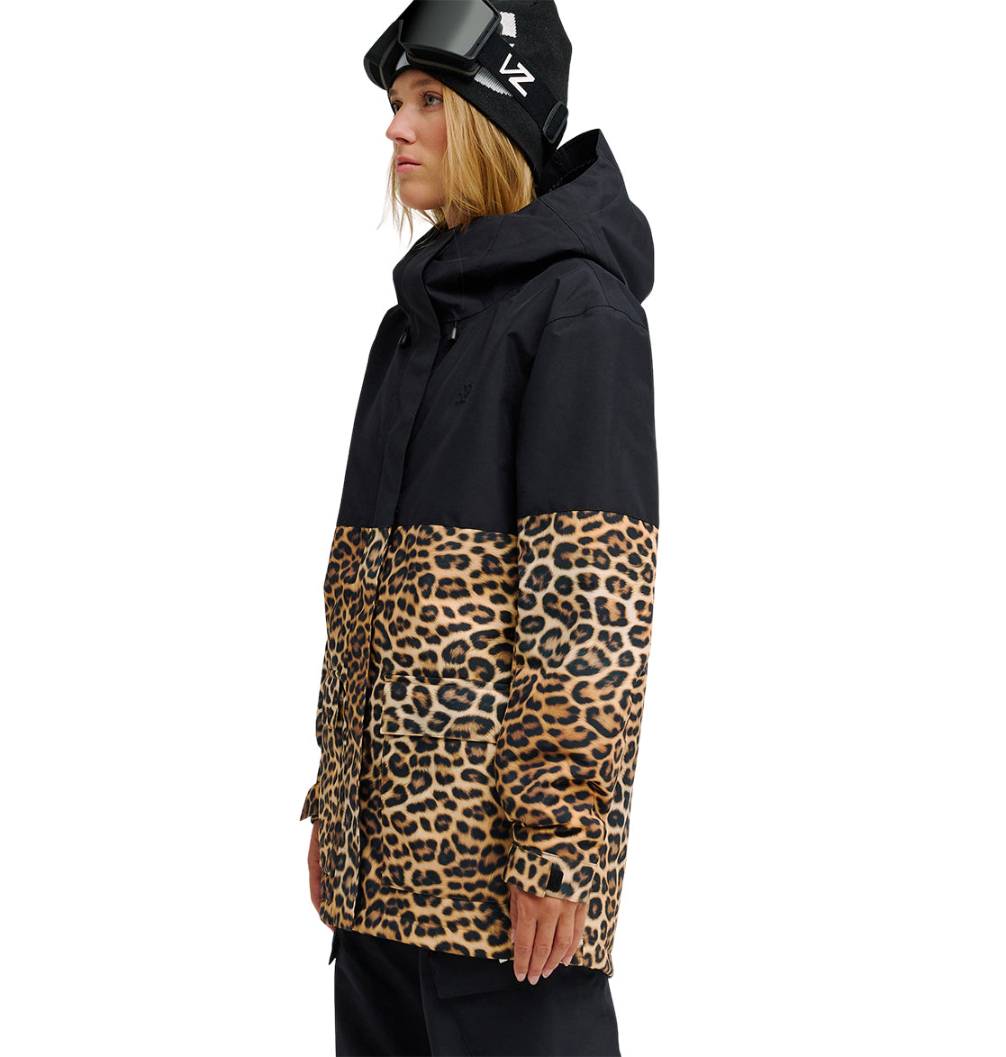 Wearing the DC Shoes Cruiser Jacket—featuring black and leopard print—a person stands facing left against a white background, paired with black pants, a black hat, and ski goggles.