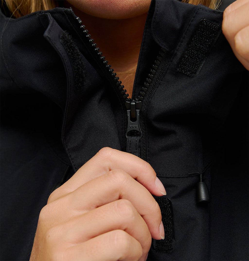 A person’s hands zip up a black DC Shoes Cruiser Jacket, focusing on the zipper and collar area. The face is mostly out of frame.