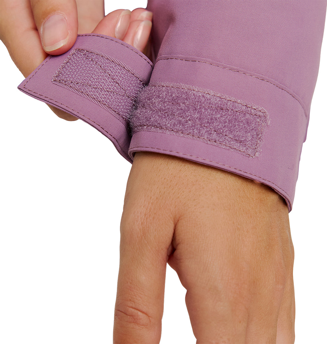 A hand adjusts the hook-and-loop fastener cuff of a long-sleeve, light purple DC Shoes Cruiser Jacket.