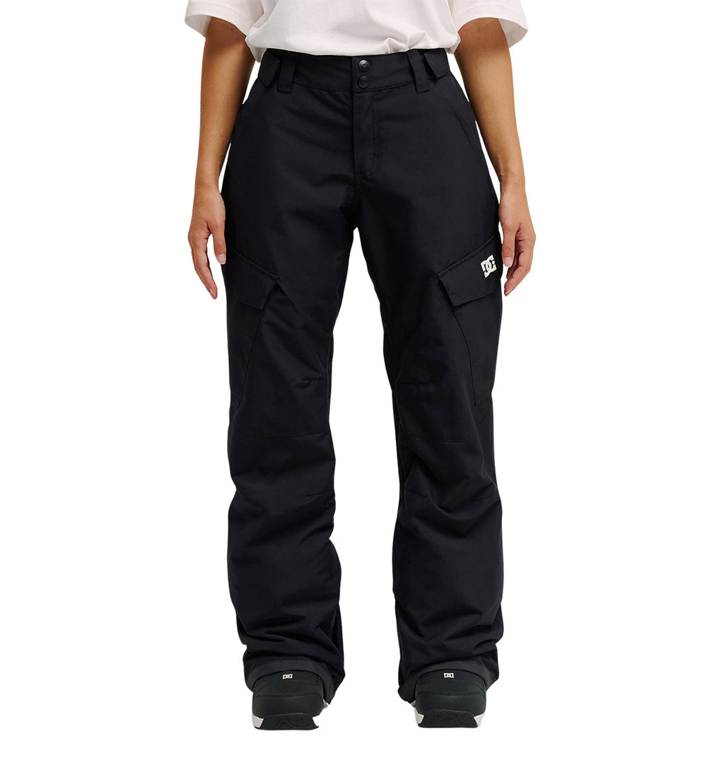 A person is shown from the waist down, wearing DC Shoes’ Nonchalant Pant in black with a white shirt. The pants are loose-fitting and insulated, featuring flap pockets and a small white DC Shoes logo on the left thigh for added style and dependable snow performance. Their arms rest relaxed at their sides.