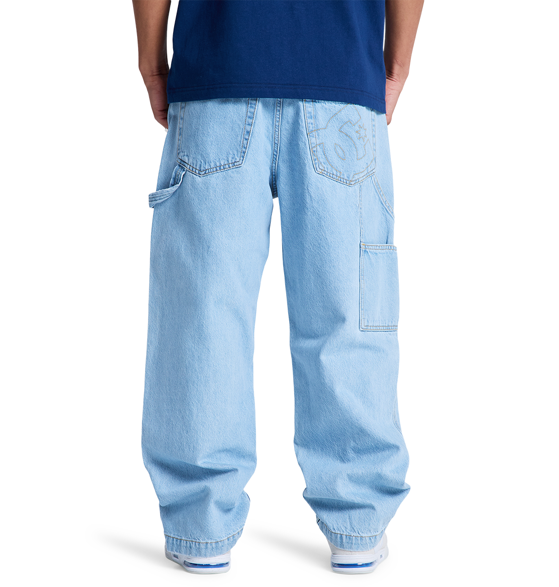 A person shown from the back against a plain white background wears DC Shoes Men's Baggy Denim Carpenter Pant in light blue with large pockets and a dark blue shirt.