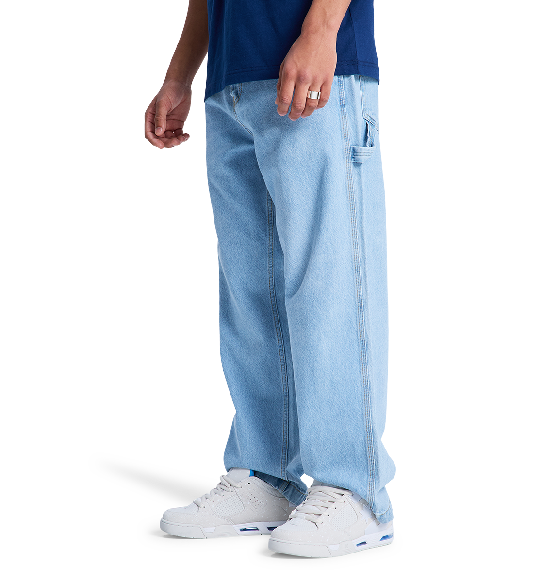 Only the lower half is visible as someone models the DC Shoes Men's Baggy Denim Carpenter Pant, a wide-leg fit jean, paired with a dark blue shirt and white sneakers against a white background.