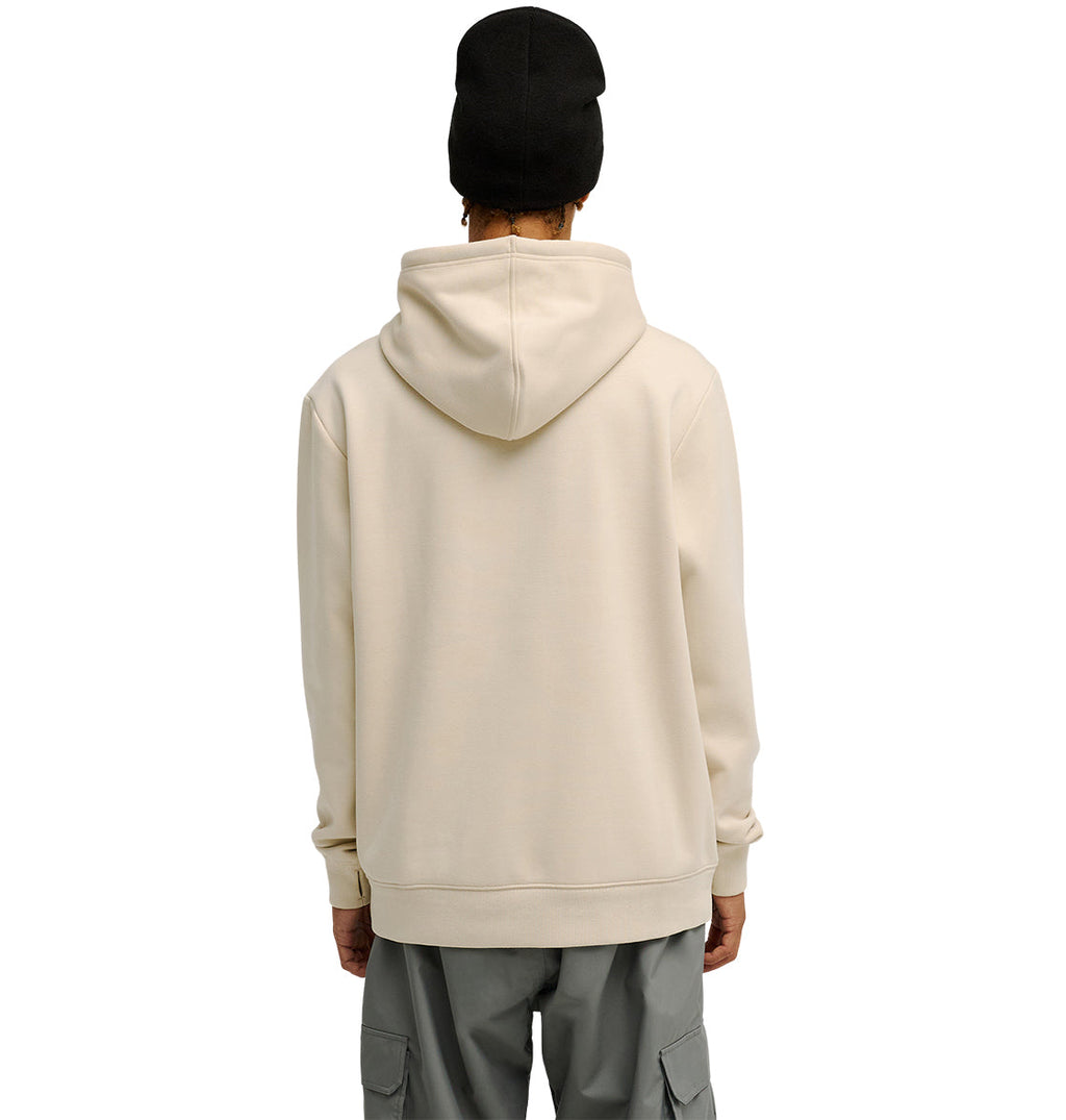 A person wearing the DC Shoes Snowstar light beige hoodie, paired with gray cargo pants and a black beanie, stands facing away against a plain white background.