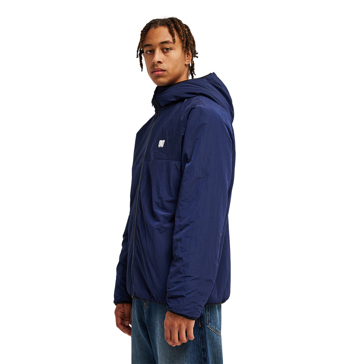 A person wearing the DC Shoes Coldstag Sherpa Reversible hooded jacket in blue and jeans stands facing slightly to the side against a white background.