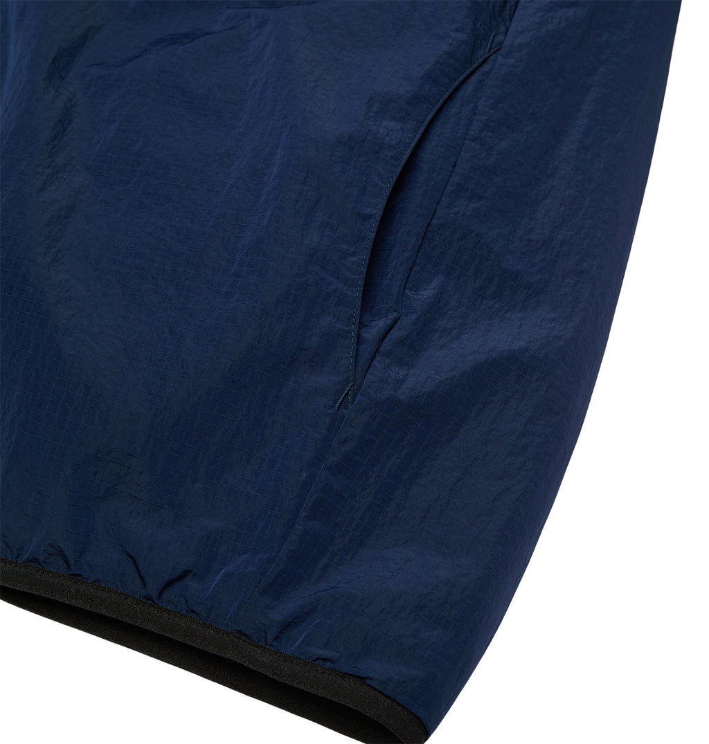 Close-up of the DC Shoes Coldstag Sherpa Reversible jacket sleeve in navy blue, featuring a visible side pocket and elastic cuff, highlighting the lightweight, subtly shiny fabric designed for cold-weather comfort.