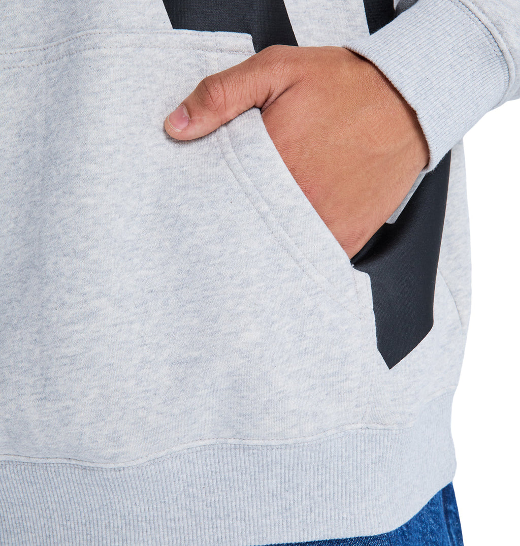 Someone wears the Reebok Lanai Ph light gray sweatshirt with one hand in the front pocket. The sweatshirt has ribbed cuffs, and it's paired with blue jeans.