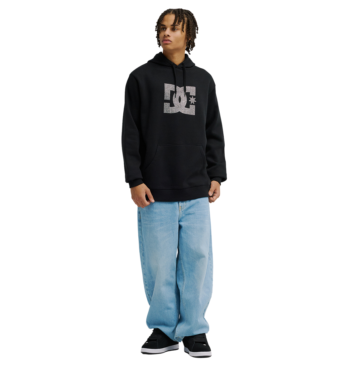 A person wearing the Men’s DC Strass Star Hoodie by DC Shoes, styled in black, pairs it with light blue baggy jeans and black sneakers while standing facing slightly to the right against a plain white background.