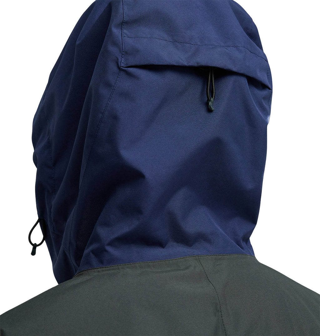 A close-up of a person wearing the DC Shoes Coldsmoke Jacket 10K in blue, shown from behind. This jacket features a drawstring hood and a dark gray upper back panel, providing breathable protection for enhanced comfort during outdoor activities.