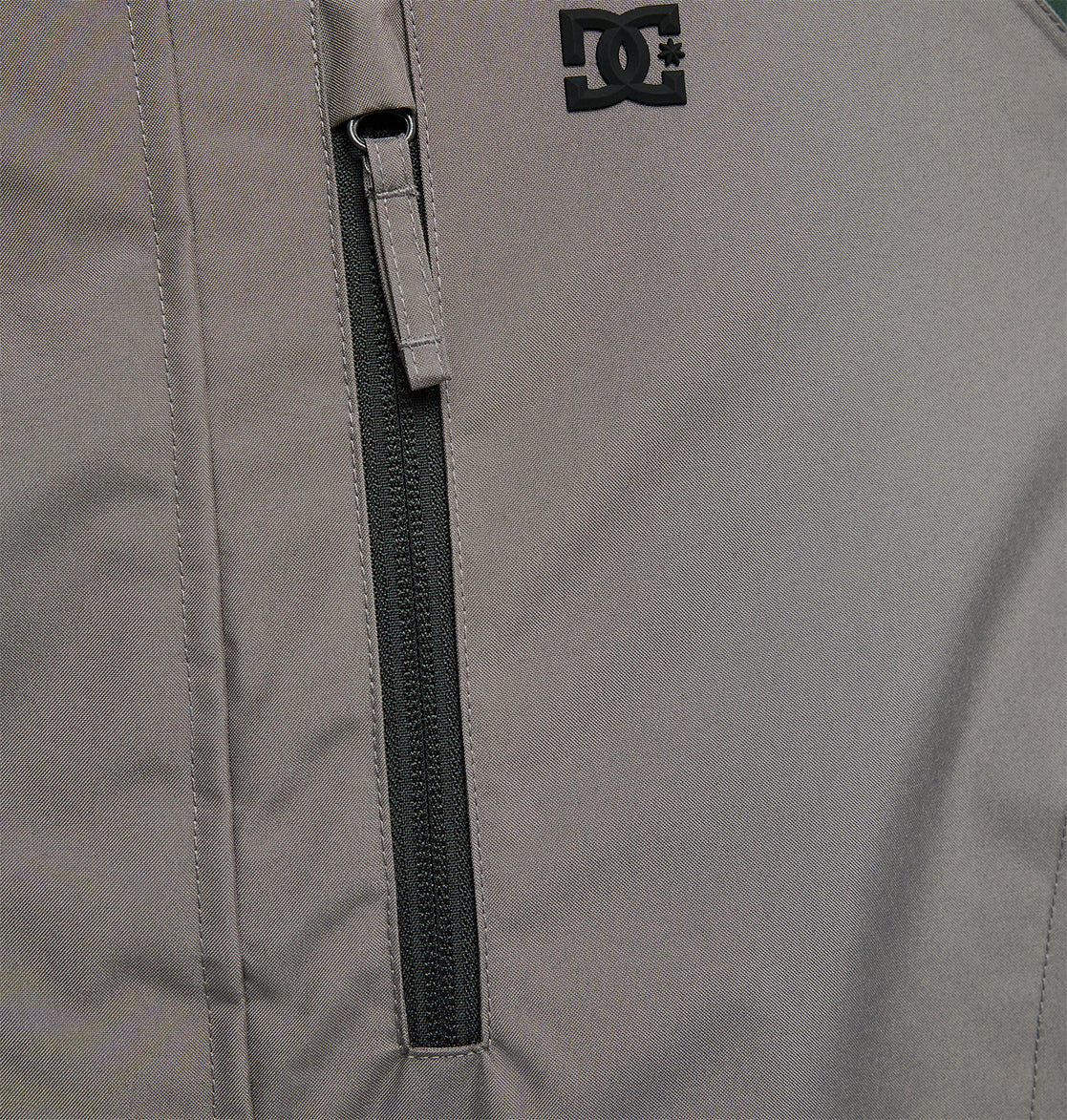 Close-up of the DC Shoes Coldsmoke Jacket 10K in gray, showcasing a vertical zippered chest pocket and a black DC Shoes logo near the shoulder, offering breathable protection against the elements.