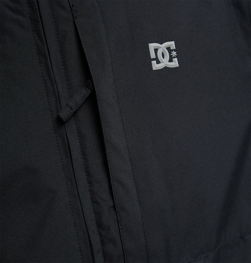 Close-up of the DC Shoes Basis Jacket 10K in black, showcasing a small white DC Shoes logo on the chest, with detailed pocket accents and visible stitching.