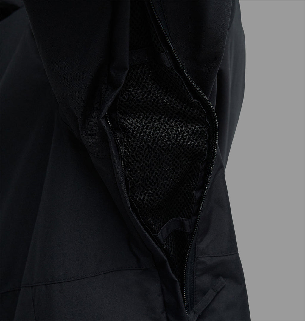 Close-up of the DC Shoes Basis Jacket 10K in black, featuring an open zipper vent with black mesh lining underneath, set against a plain gray background.