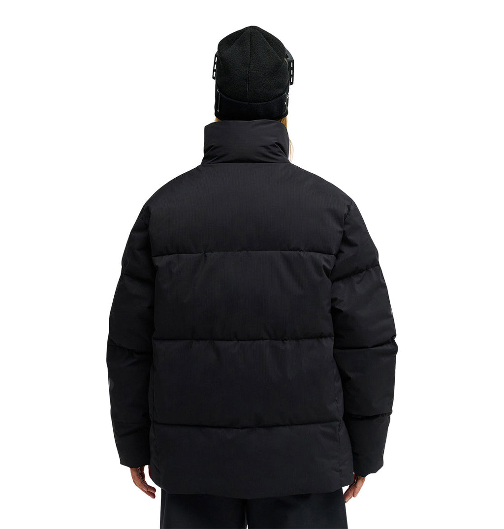 Wearing the DC Shoes Trackstar Puffer 10K jacket and a black beanie, a person stands with their back to the camera against a plain white background, highlighting both style and snow-ready performance.