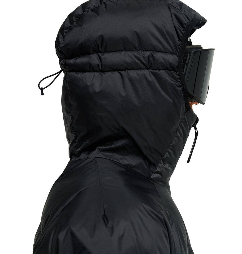 A person wearing the DC Shoes Powder Puffer 10K jacket, featuring a hood for breathable protection, paired with black ski goggles. Side profile view against a plain background.