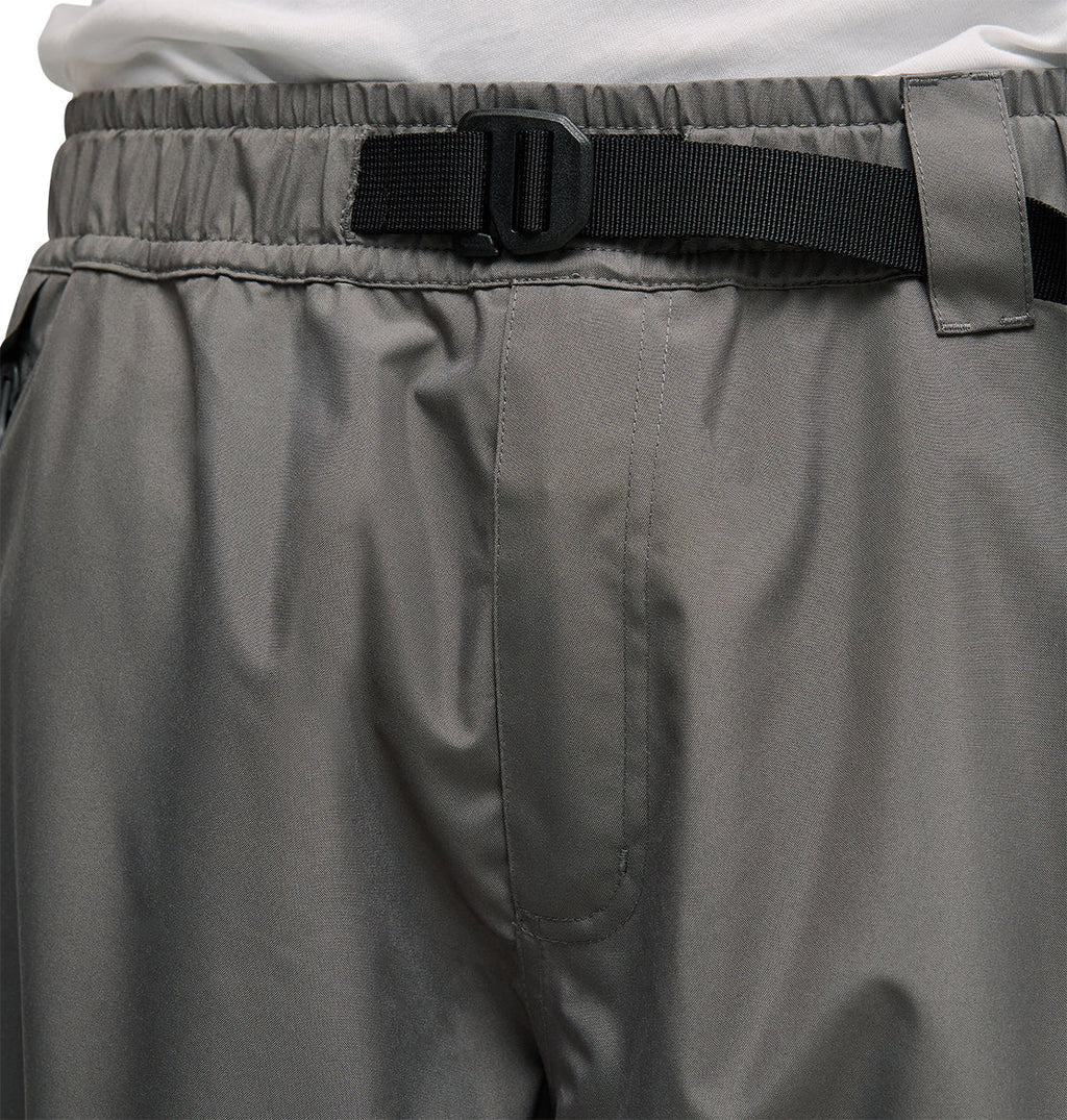 Close-up of a person wearing DC Shoes Smoke Pants 10K in gray—breathable snow pants featuring an elastic waistband, black adjustable belt, and a white shirt tucked in at the waist.