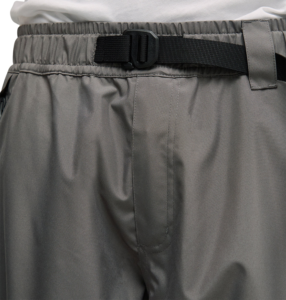 Close-up of a person wearing DC Shoes Smoke Pants 10K in gray—breathable snow pants featuring an elastic waistband, black adjustable belt, and a white shirt tucked in at the waist.