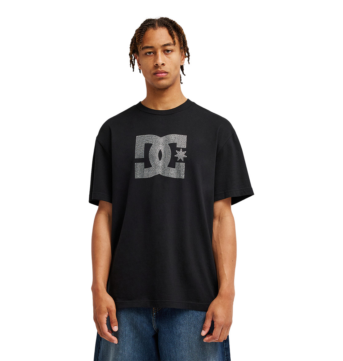 A person stands facing forward against a plain white background, wearing the Men’s DC Strass Star Tee by DC Shoes—a relaxed fit black graphic skate tee featuring a rhinestone DC star—paired with blue jeans.