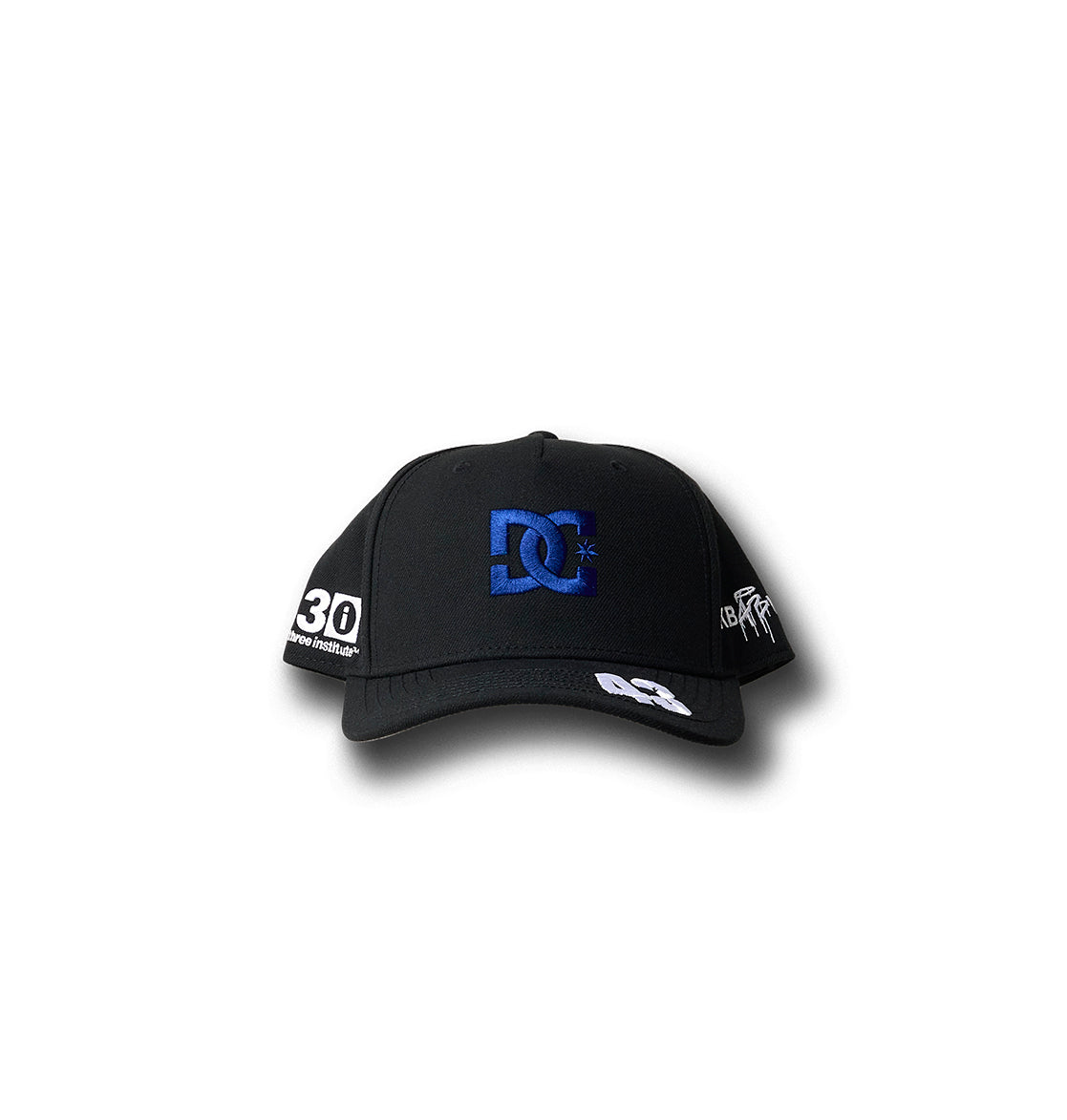 The KB 43 Snapback by DC Shoes is a black baseball cap with a blue DC Shoes logo on the front, white "30" patch on the left, and BLOCK Rally Teamworks graphics on the right and bill, shown against a white background.