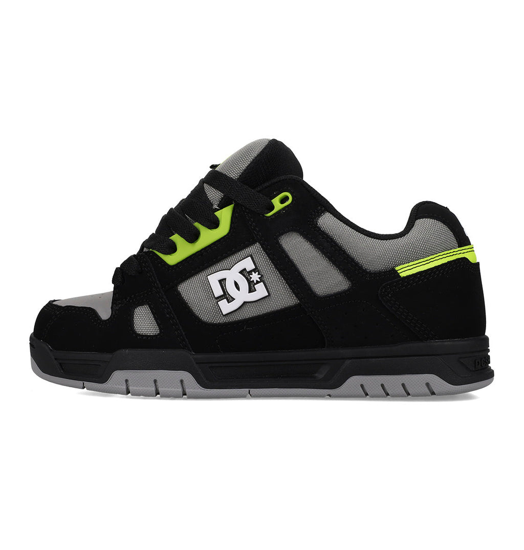 Black sneaker with green accents and a visible brand logo on a white background